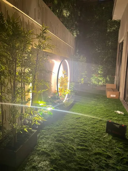I design green spaces that feel magical, day or night. This residential garden project features my soft artificial turf, complemented by strategic lighting on the surrounding artificial plants and a modern circular sculpture.