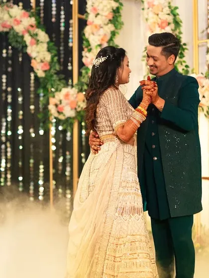 The couple's romantic dance at their Sangeet. Framed by a beautiful floral arch and sparkling lights, they are lost in their own world, creating a picture-perfect memory.