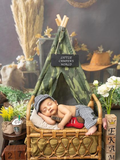 A little camper taking a nap. This adorable setup features a newborn sleeping in a rustic bed, ready for a woodland adventure.