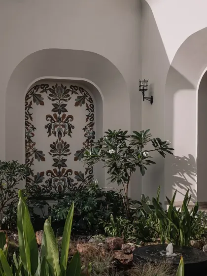 A glass mosaic fresco installed in an outdoor courtyard. The traditional motifs, rendered in a contemporary palette, create a timeless piece of art that harmonizes with the surrounding nature.