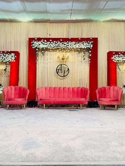 Classic and bold, this engagement stage uses a striking red and white color scheme. The setup features a clean backdrop with red panels, white floral arrangements, and plush pink seating for a touch of modern luxury.