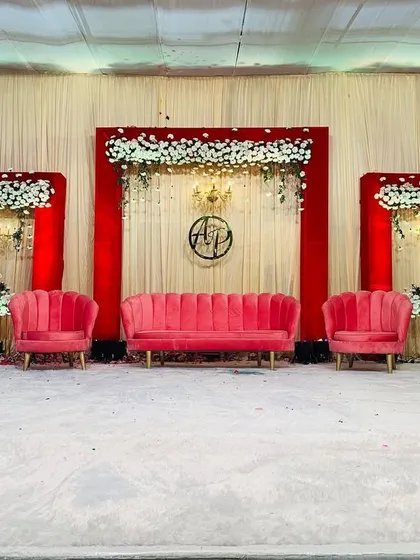 Classic and bold, this engagement stage uses a striking red and white color scheme. The setup features a clean backdrop with red panels, white floral arrangements, and plush pink seating for a touch of modern luxury.