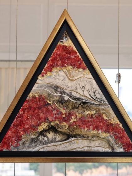 A triangular abstract resin artwork from 'A Symphony of Colour', featuring red, gold, and white geode-like patterns.