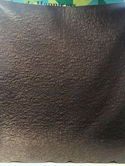 The solid brown backing of the Bargello quilt, which makes the swirling quilting pattern clearly visible.