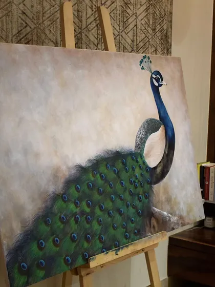 The finished peacock canvas resting on the easel in my studio space. This angle shows the scale of the painting and how it commands attention even before it's hung on a wall.