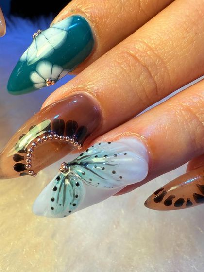 This is where our creativity truly shines. This intricate set features a mix of hand-painted floral patterns, 3D butterfly wings, and delicate beadwork, all on long, beautifully shaped nail extensions.