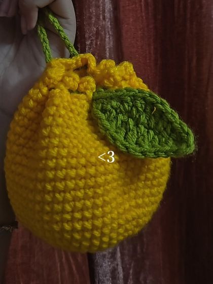 A slightly different angle of the lemon drawstring pouch, showing how it closes up. It’s a fun and fruity accessory that always makes me smile.