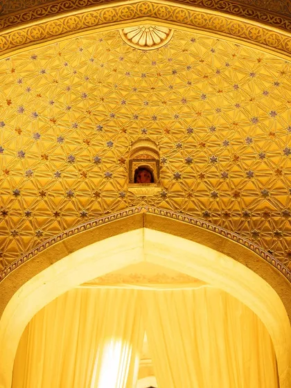 The mesmerizing, geometric patterns of a domed ceiling inside the palace, glowing with warm light. These details add to the opulence of a destination wedding.