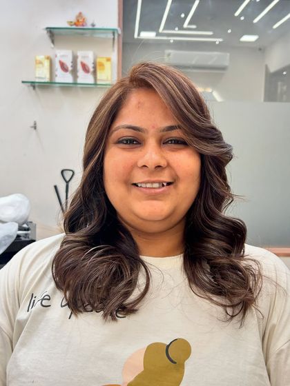 A frontal view of a beautiful hair color makeover. The highlights frame her face, and the voluminous curls add a touch of glamour.