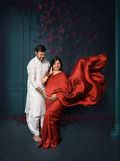 A dynamic shot featuring a flowing red saree. We tossed the fabric to add a sense of movement and drama to this traditional couple's portrait, blending classic elegance with modern artistry.