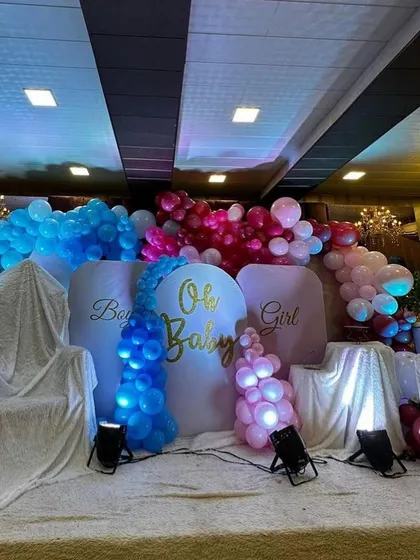 A stage setup for a "Boy or Girl" gender reveal party. I used dramatic blue and pink lighting to highlight the respective balloon colors, creating an exciting and theatrical backdrop for the big announcement.