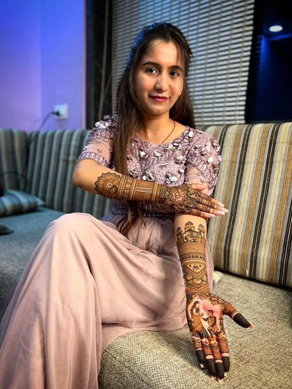 A client posing on a couch, showcasing her elegant full-arm mehandi.