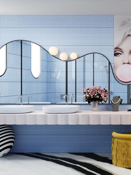 The double vanity is a statement piece, with a long, wavy mirror and quirky yellow stools adding a pop of color.