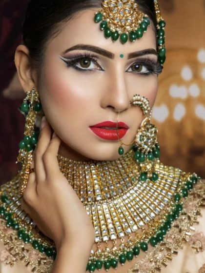 A striking look with a green-beaded choker against a beige outfit. The bold red lip and winged eyeliner complete this glamorous style.