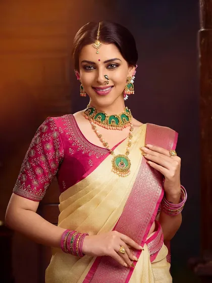 This portrait showcases a different jewelry set against the same beautiful saree. The green enamel work in the necklace and earrings offers a striking contrast to the pink blouse.
