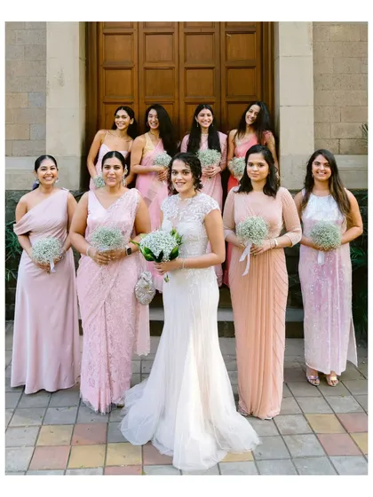 The bride with her bridesmaids, all dressed in shades of pink, standing outside the church. A beautiful portrait of friendship and support.