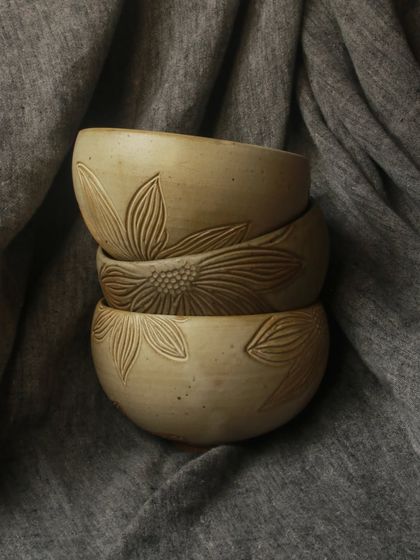 A stack of hand carved bowls from the 'Gulbaan' collection, showcasing the delicate floral details that define Bhavya's elegant and earthy style.