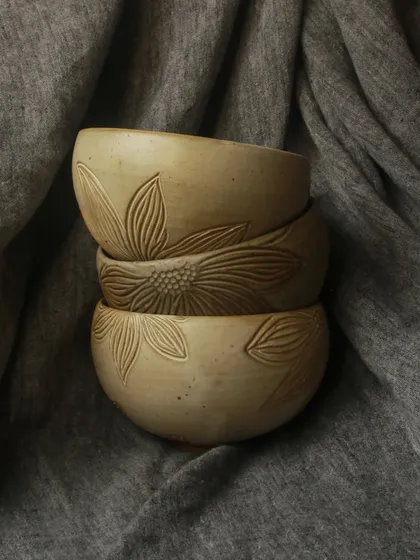 A stack of bowls from the 'Gulbaan' Collection, showcasing the delicate hand-carved floral details. Each piece is a celebration of earth and bloom.