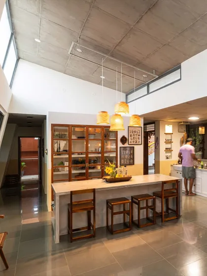 The open-plan kitchen and dining area of "Aamra," where the service and served spaces blend. The central island, with its cement oxide top and upcycled pantry shutters, acts as the social heart of the home.