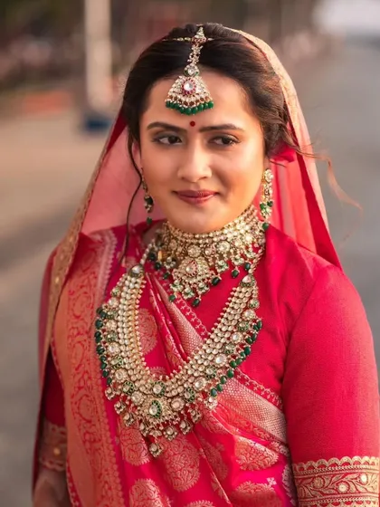 This bride's look was all about royal elegance. The makeup features a classic winged liner and a bold lip, paired with a traditional red saree and heavy jewelry for a truly regal appearance.