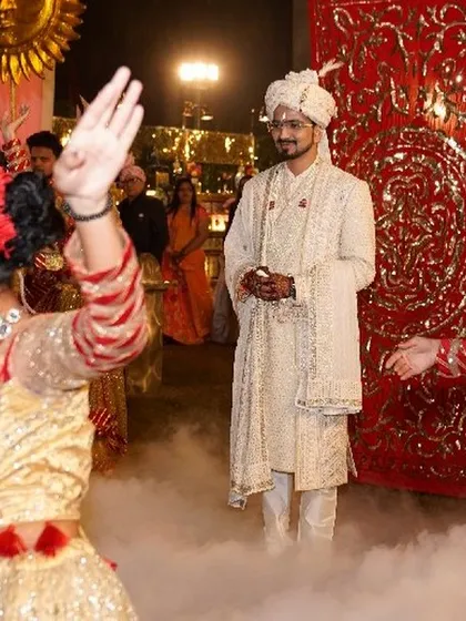 A close-up moment during the groom's entry, where he is the calm center of a whirlwind of dance and smoke. This captures the personal experience within the grand spectacle.