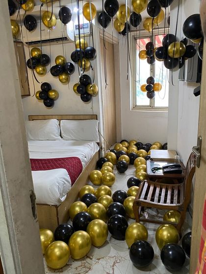 This view from the doorway shows the impressive sight of a room completely filled with black and gold balloons for a grand birthday surprise.