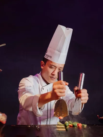 Precision and passion are the tools of our trade. Here, one of our chefs expertly prepares a dish on a teppanyaki grill, showcasing the skill and focus that goes into every plate we serve.