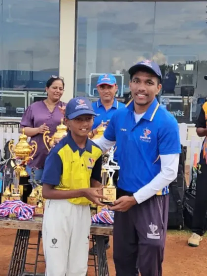 A coach congratulates a young award winner during the PTPL prize distribution ceremony, surrounded by teammates and parents.