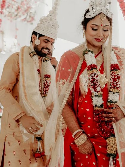 A full-length shot of the couple during their Bengali wedding ceremony, showcasing their traditional attire.