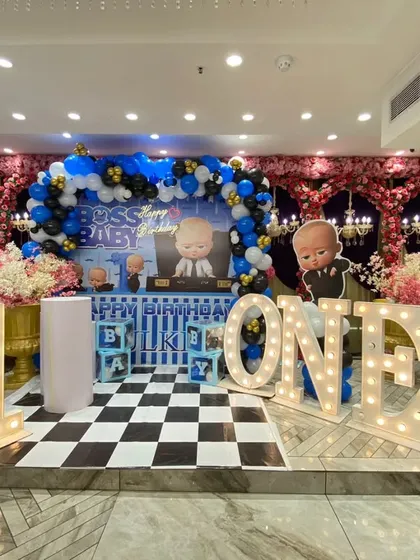 A full stage view of the Boss Baby first birthday party. The setup is perfectly symmetrical, with marquee letters, character props, and a balloon arch creating a grand photo backdrop.