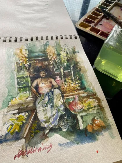 The banana seller sketch in my Brustro sketchbook, with my watercolor palette nearby. These daily life scenes are among my favorite subjects.