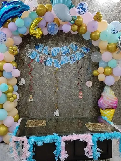 An under-the-sea themed birthday decoration for a 4th birthday. I created a balloon arch with pastel and gold balloons, adding dolphin and ice cream foil balloons for a fun touch over the cake table.