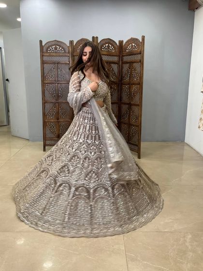A dynamic shot capturing the twirl of this heavily embroidered grey lehenga. It shows the incredible craftsmanship and the sheer amount of fabric in this pre-loved designer piece.