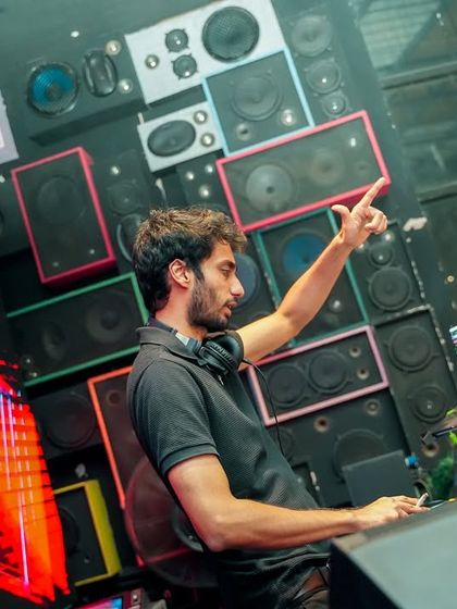 Pointing to the sky, surrounded by a wall of speakers, during a high-energy NYE set.