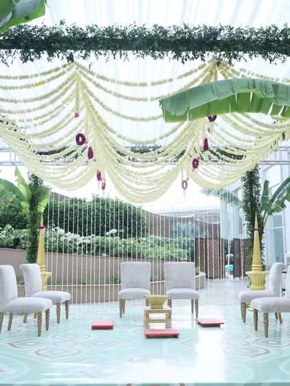 This traditional mandap is designed with serene South Indian aesthetics. A canopy of white floral strings and banana leaves creates a sacred space, perfect for a culturally rich and beautiful outdoor wedding ceremony.