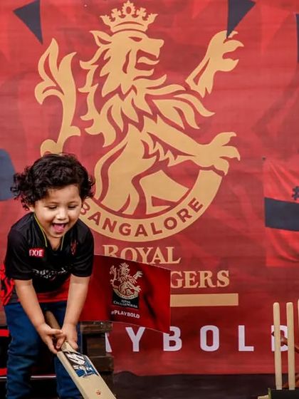 A great action shot from the RCB cricket theme, capturing the little fan's excitement as he swings the bat.
