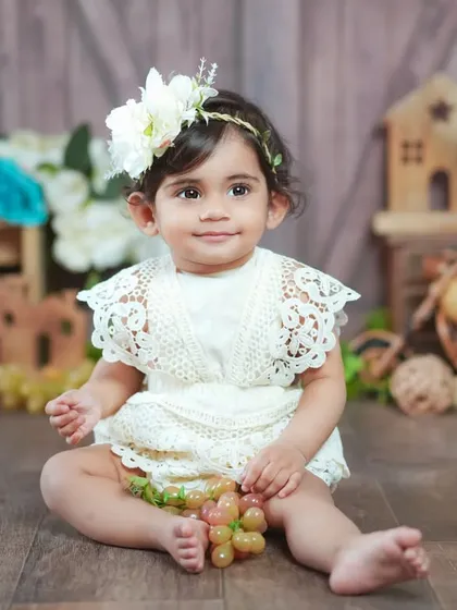 A vintage-inspired portrait in a beautiful lace romper. The soft lighting and rustic props create a timeless feel.