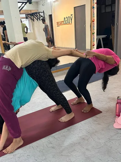 A three-person backbend, where one student acts as a supportive base, allowing another to deepen her Urdhva Dhanurasana (Wheel Pose).