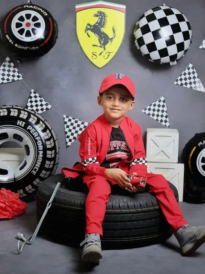A cool and confident pose from the birthday boy during his race car-themed photoshoot. He's sitting on a tire, looking like a true professional racer.