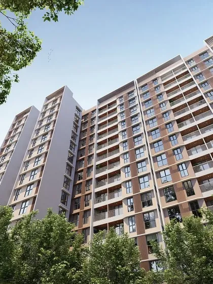 A ground-level perspective of the Kohinoor Uptown residential towers. The facade design and building orientation are planned to maximize natural light and ventilation, while the surrounding trees create a feeling of living within a park.