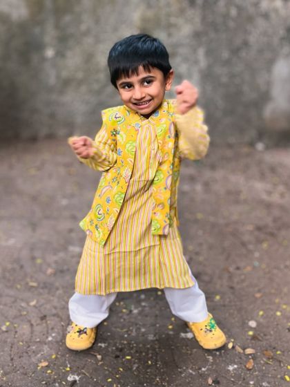 This little guy is full of energy in his yellow striped kurta and floral bandi jacket. The set is designed to be lightweight and non-restrictive.