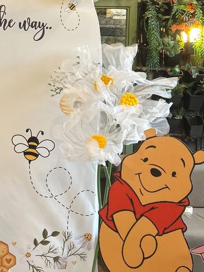 A detailed shot of our Winnie the Pooh baby shower theme, showing the character cutout and custom-made fabric daisies.