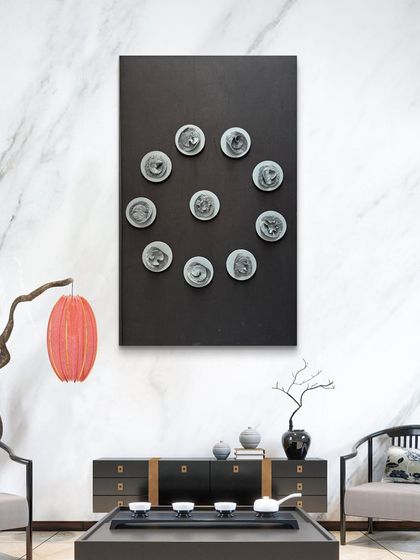 The Navagraha piece in a modern living room with a marble wall. The contrast of the dark frame and sculpted circles creates a striking visual.