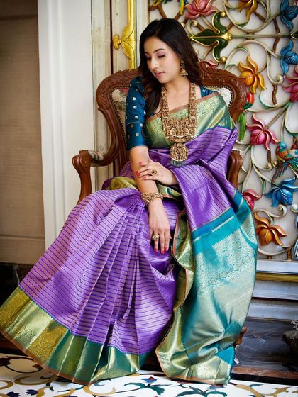 Seated in a beautifully carved chair, Dr. Shruthi's saree drapes elegantly around her, a picture of regal poise.
