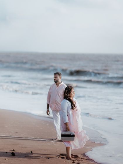 A beautifully composed wide shot of a couple on the beach, looking out at the ocean, capturing a sense of shared dreams and future.