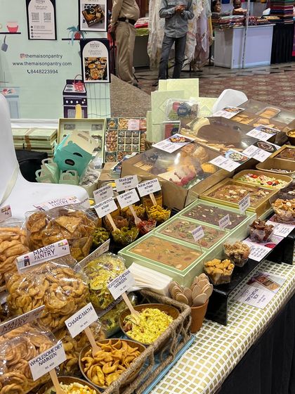 A wide shot of my beautifully arranged stall at the FICCI FLO exhibition. I displayed a wide range of products, from savory snacks and pickles to my signature mithai bars.