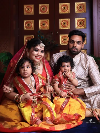 A complete family portrait celebrating Janmashtami. The parents are seated with their two young children, who are delightfully dressed as little Krishnas, showcasing our ability to create beautiful themed shoots for the whole family.