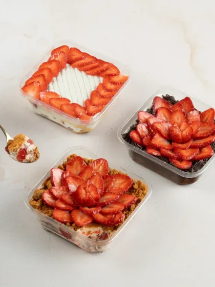 Dig into our made-to-order desserts loaded with fresh strawberries. Pictured here are our Strawberry Biscoff Cheesecake, Strawberry Tres Leches, and Traditional Chocolate Strawberry Gateau tubs.