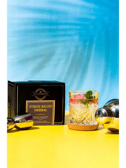 This shoot for a stress relief herbal tea uses a modern, high-contrast style with bold yellow and blue colors. The refreshing iced tea in a crystal glass suggests a cool, calming experience, perfect for a summer wellness product.