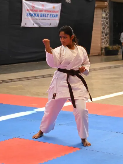 A student demonstrates a powerful stance during her brown belt examination. Her focus and form show she is ready for the next level.